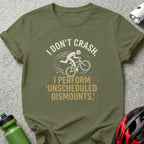 Olive t-shirt with white text "I DON'T CRASH. I PERFORM UNSCHEDULED DISMOUNTS." and cyclist graphic.