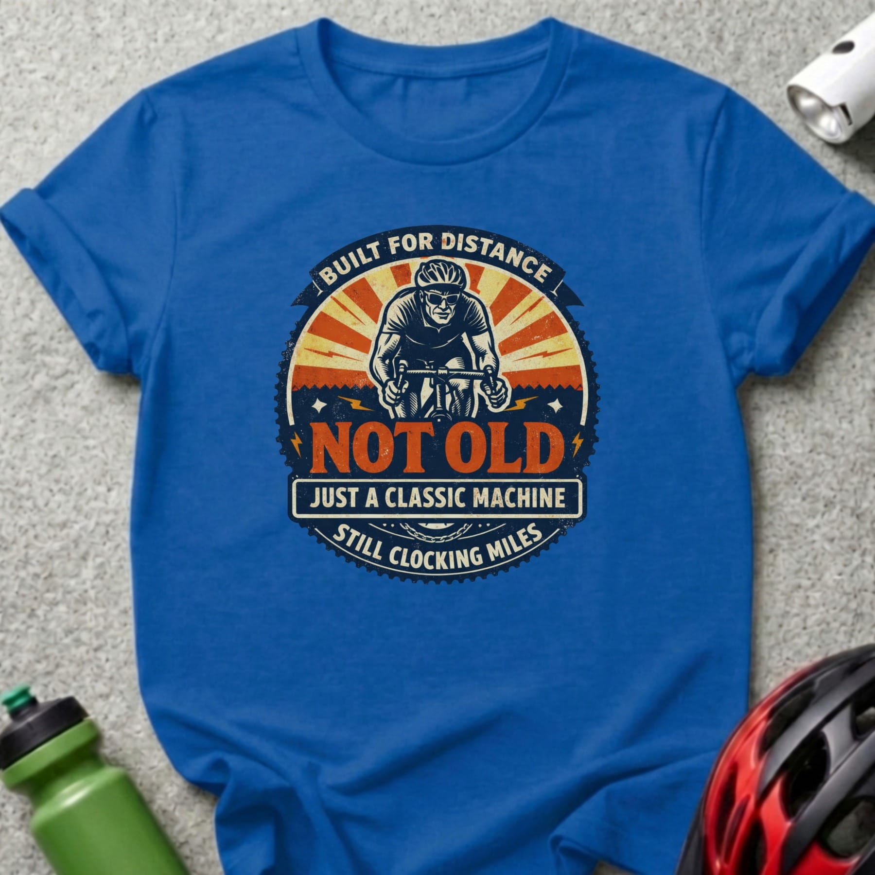 Blue t-shirt with "Built for Distance, Not Old, Just a Classic Machine, Still Clocking Miles" text and cyclist graphic.