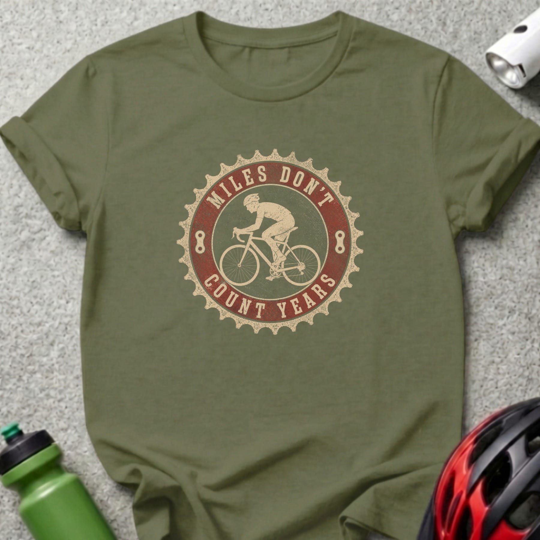 Olive green t-shirt with "Miles Don't Count Years" cycling graphic on chest.