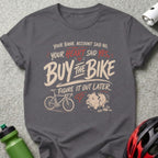 Dark grey t-shirt with "Buy the Bike" text and a bicycle and piggy bank graphic.