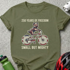 Green t-shirt with dog on bicycle, "250 Years of Freedom Small But Mighty."