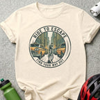 Circular graphic on t-shirt: "Ride to Escape, Find Your Way Out" with cyclist on city street.