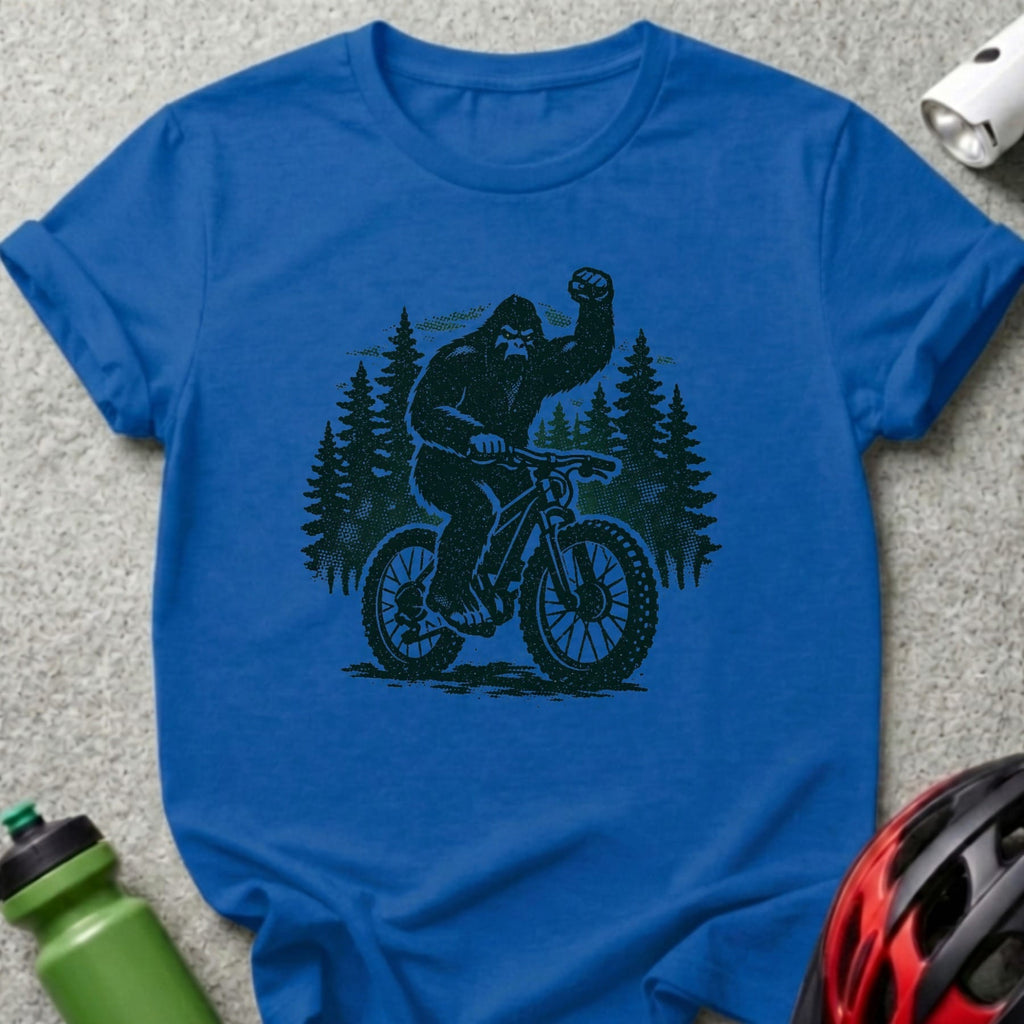 Black Bigfoot riding a mountain bike with trees behind him.