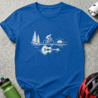A blue t-shirt with a white graphic showing a cyclist, trees, sun, and an acoustic guitar reflection.