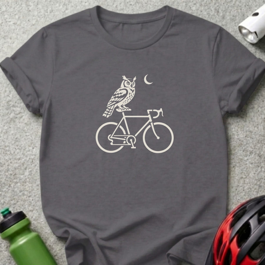 A charcoal gray t-shirt featuring a white graphic of an owl perched on a bicycle with a crescent moon overhead.