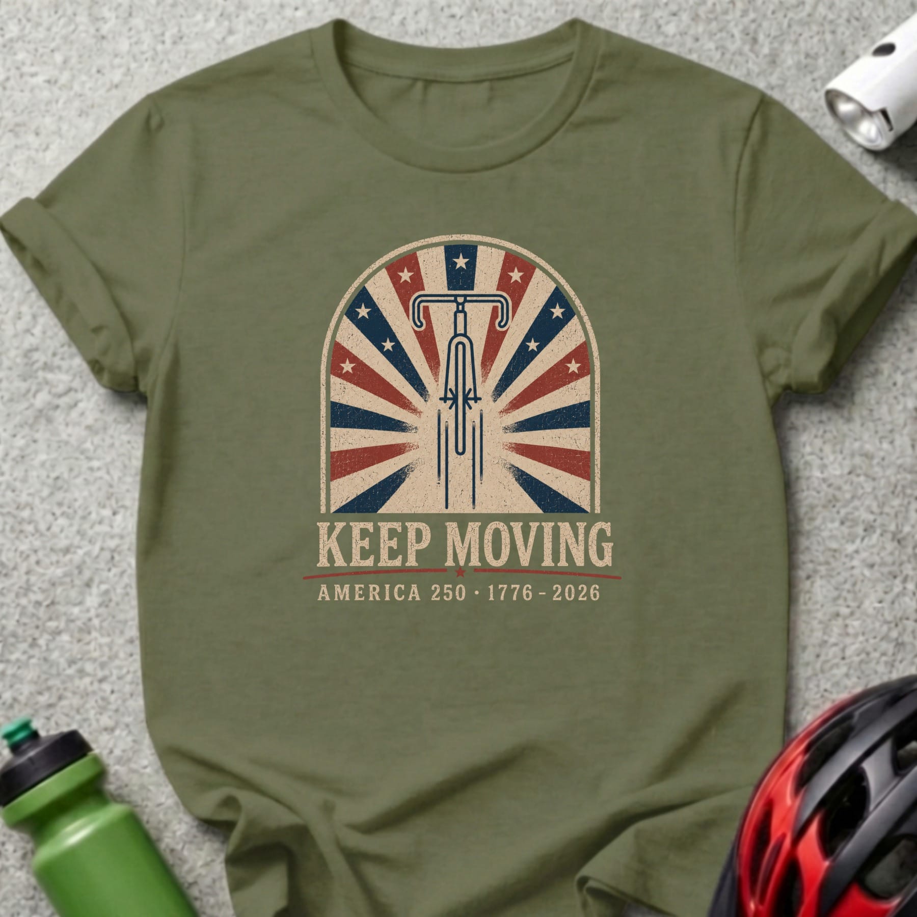 Green t-shirt with "Keep Moving America 250 - 1776 - 2026" text and bicycle wheel graphic.