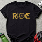 Black t-shirt with gold graphic that spells out "RIDE" with bicycle elements.
