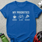 Blue t-shirt with white text and icons: coffee, bicycle, pizza, and "My Priorities".