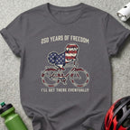 Dog on bicycle with American flag pattern, "250 Years of Freedom. I'll get there eventually."