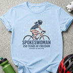 Light blue t-shirt with "SPOKESWOMAN 250 YEARS OF FREEDOM" and a cyclist wearing a US flag helmet.