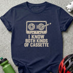 Navy blue t-shirt featuring a cassette tape graphic with bicycle gears for reels, accompanied by text reading I KNOW BOTH KINDS OF CASSETTE.