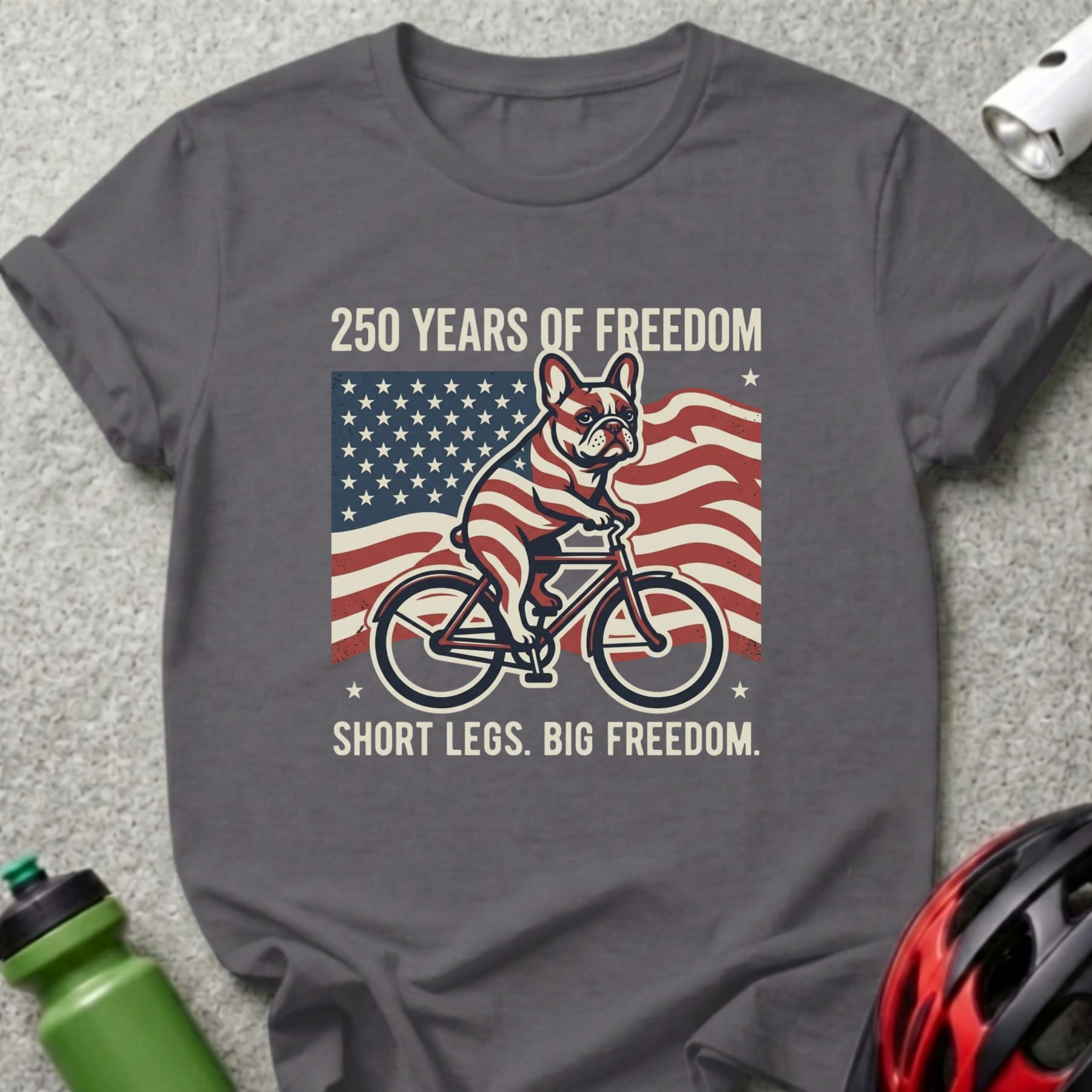 French bulldog on bicycle with American flag, "250 Years of Freedom. Short legs. Big freedom."