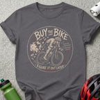 "Buy the bike, figure it out later" text with cyclist and piggy bank illustration on t-shirt.