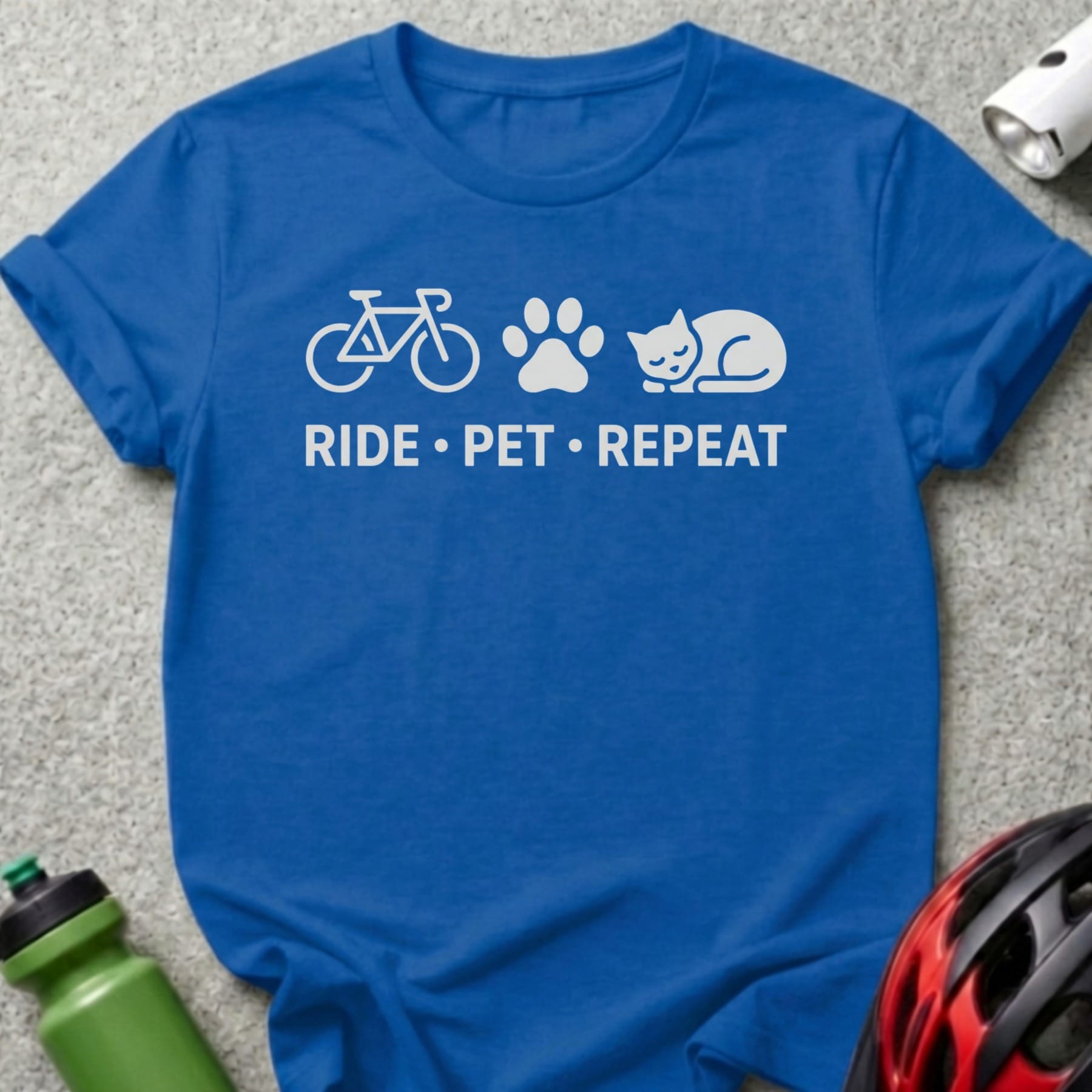 Blue t-shirt with white bicycle, paw print, and cat design and text "RIDE • PET • REPEAT".