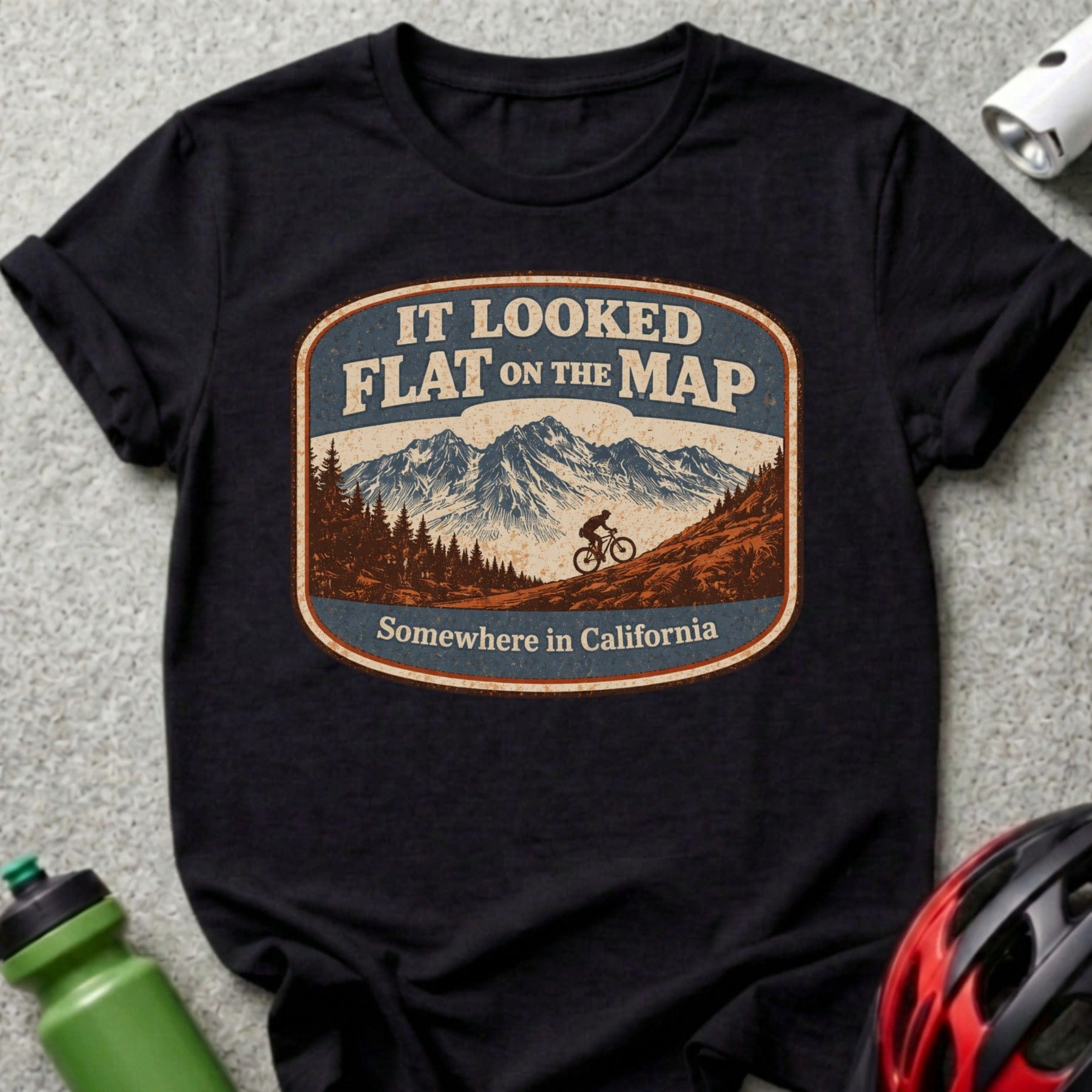 T-shirt with "It looked flat on the map. Somewhere in California" text and mountain biking scene.
