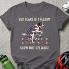 Grey t-shirt with American flag dog riding a bicycle, text "250 Years of Freedom" and "Slow But Reliable".