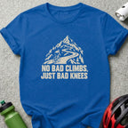 Blue t-shirt featuring a white graphic of a cyclist climbing a mountain road with the text NO BAD CLIMBS, JUST BAD KNEES.