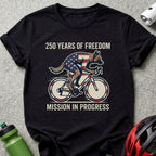 German Shepherd on a bicycle with American flag colors, "250 Years of Freedom" text.