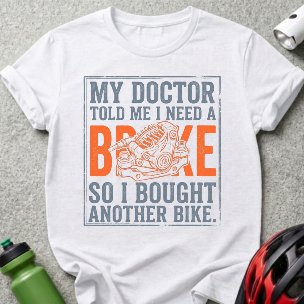 White t-shirt with text "MY DOCTOR TOLD ME I NEED A BRAKE SO I BOUGHT ANOTHER BIKE" and bike brake graphic.