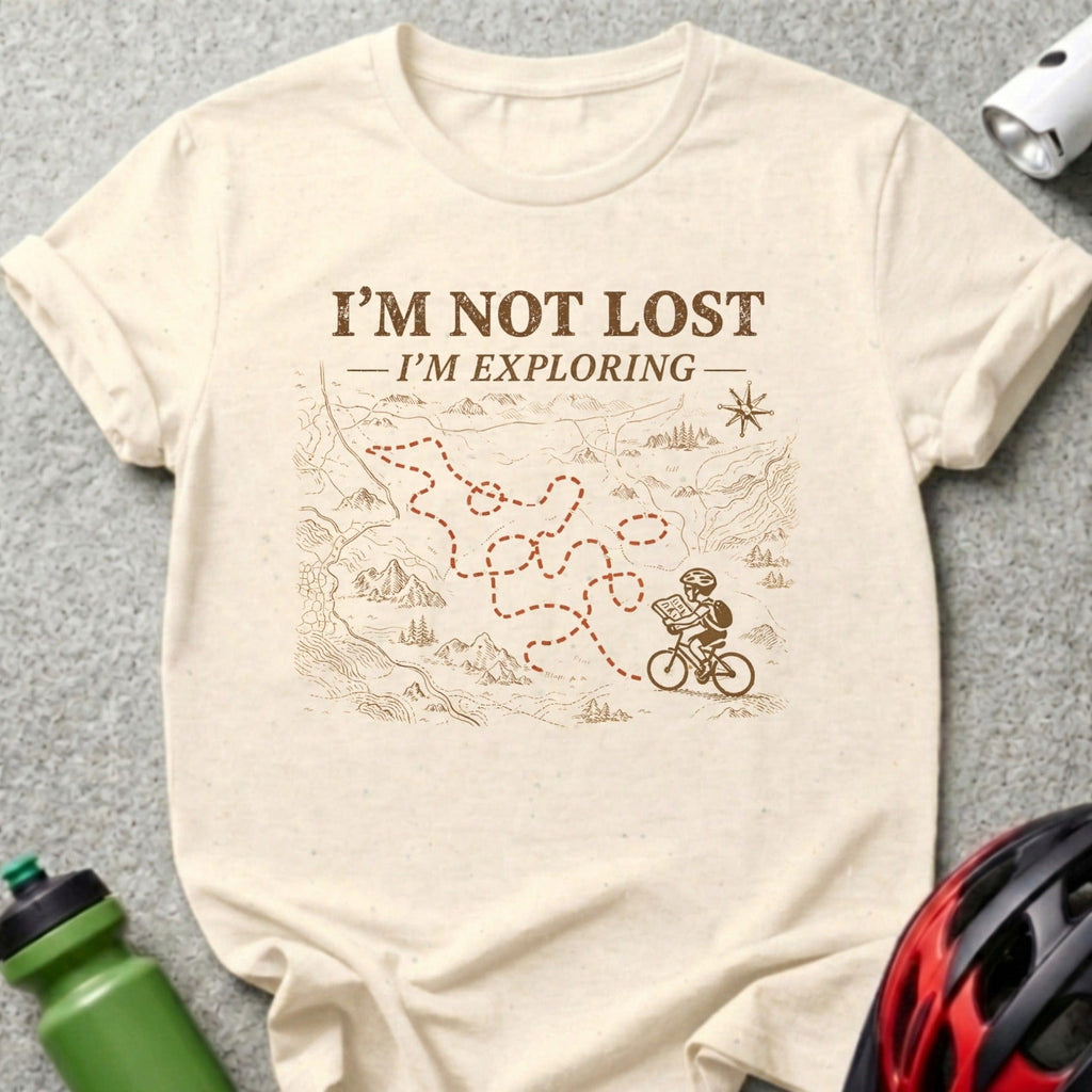 Cream t-shirt with map design and cyclist, reads "I'm not lost, I'm exploring."