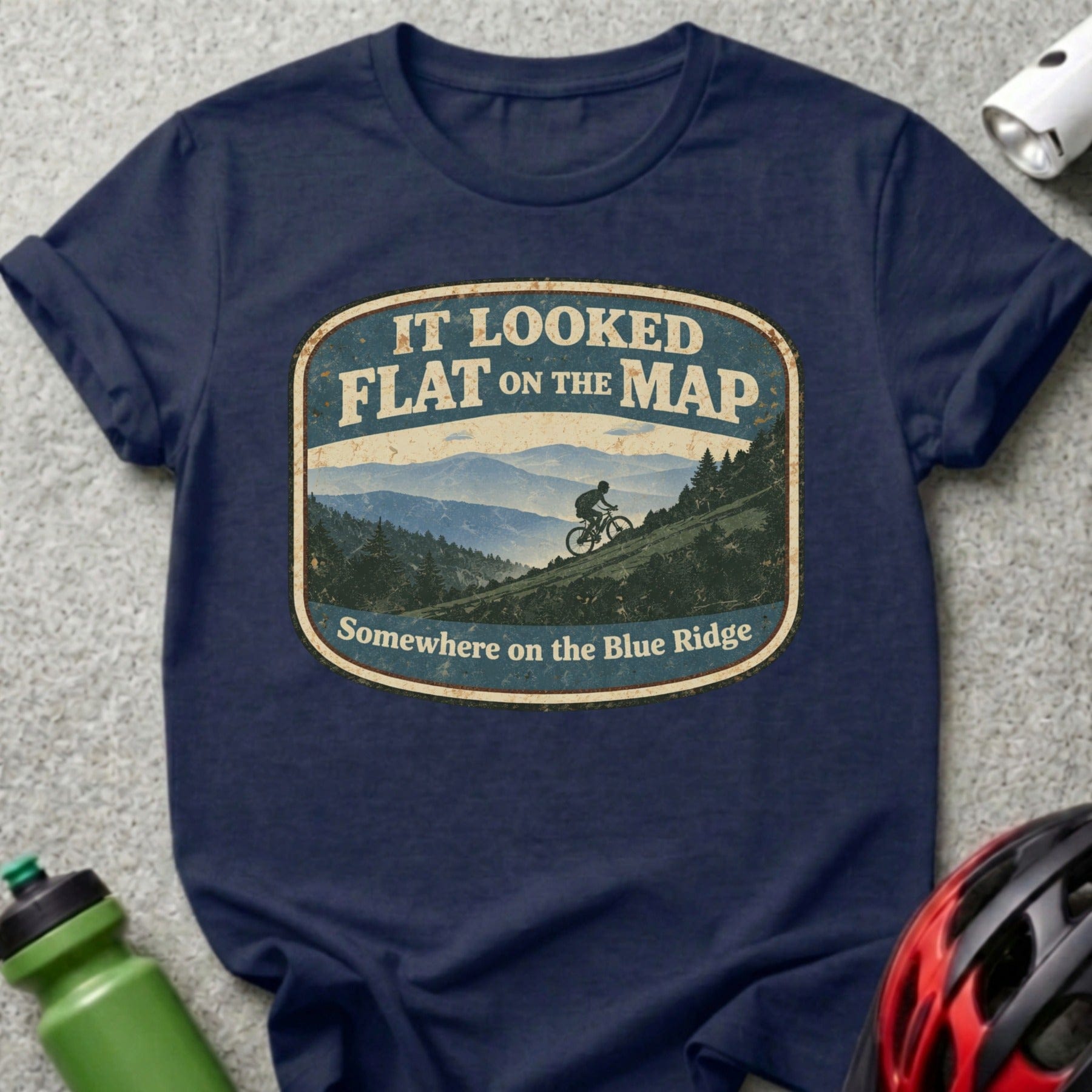Navy t-shirt with distressed oval graphic reading "It Looked Flat on the Map" and mountain biker.