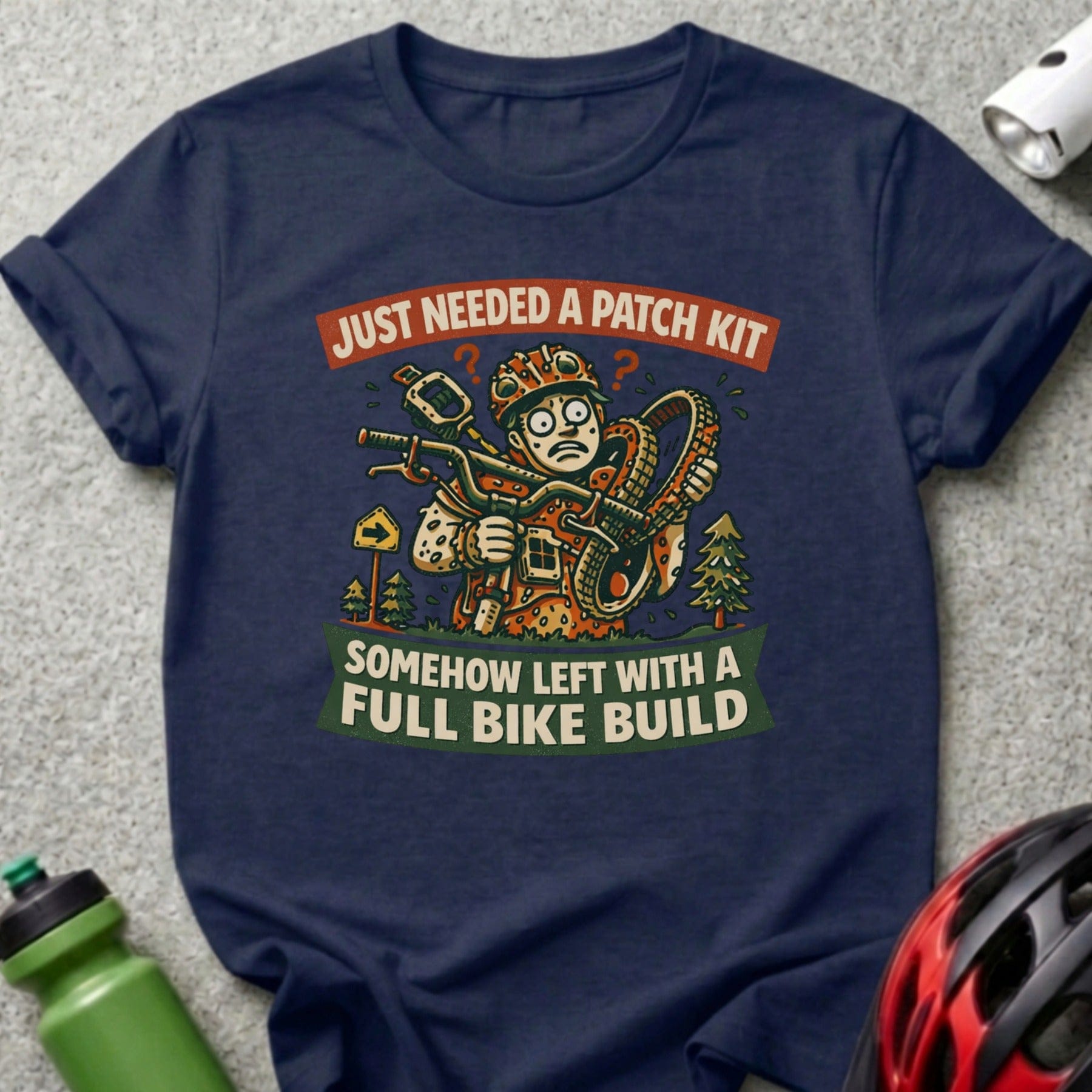 T-shirt with cartoon man holding bike parts and text "Just needed a patch kit, somehow left with a full bike build".