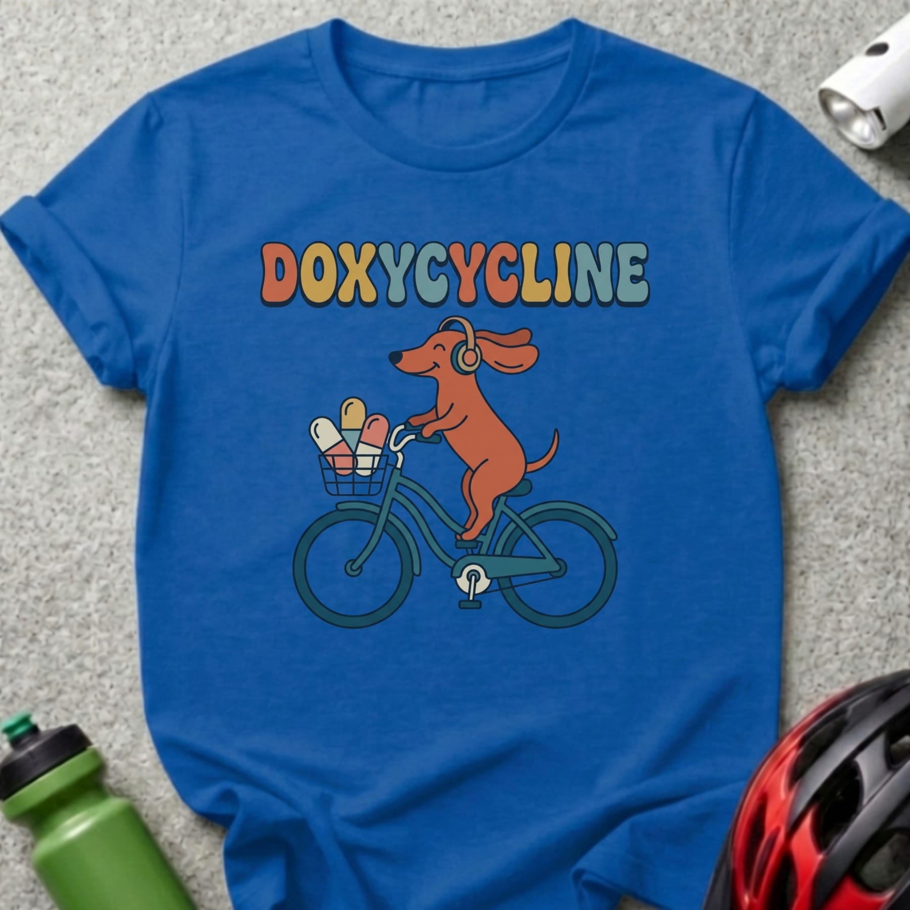 Blue t-shirt with cartoon dog in headphones riding a bicycle with pills.