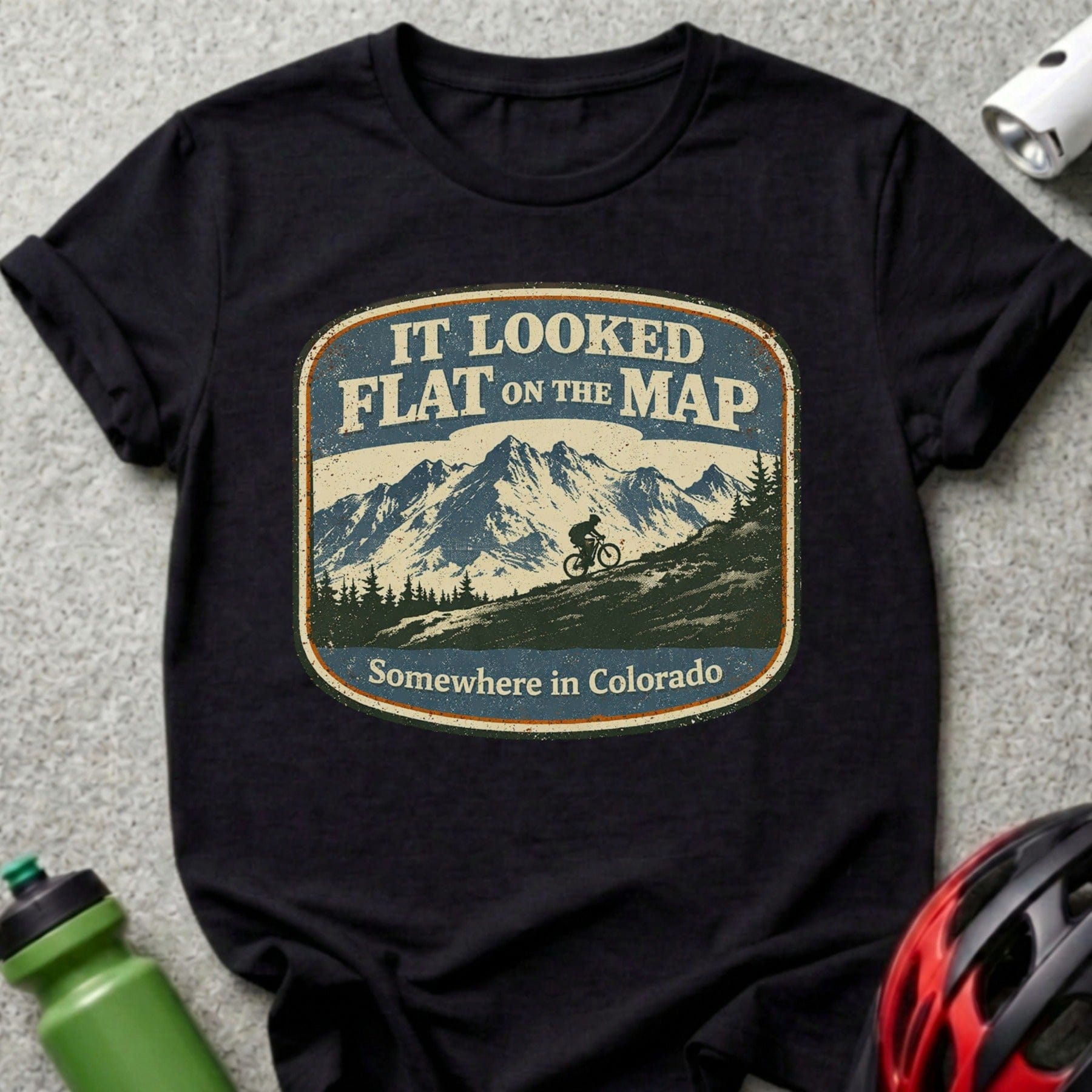 T-shirt with a mountain bike scene and text "IT LOOKED FLAT ON THE MAP Somewhere in Colorado".