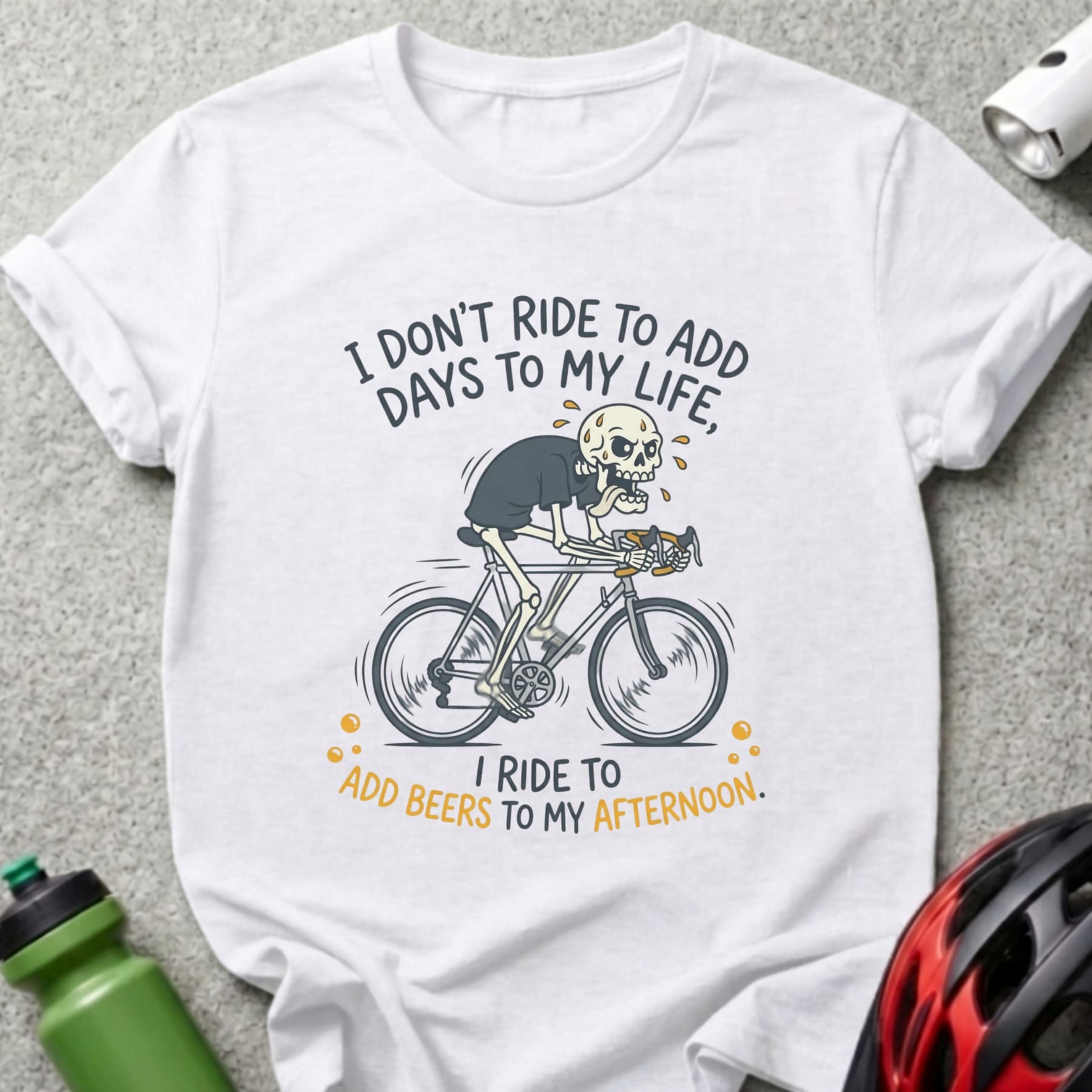 White t-shirt with skeleton on bicycle and text: "I don't ride to add days to my life, I ride to add beers to my afternoon."