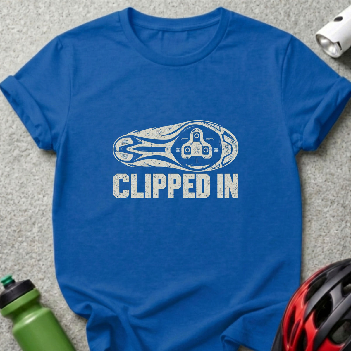 A blue t-shirt featuring a graphic of a bicycle cleat sole and the text CLIPPED IN.