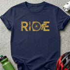 Navy t-shirt with gold "RIDE" graphic featuring a chain, bicycle wheel, and cyclist.