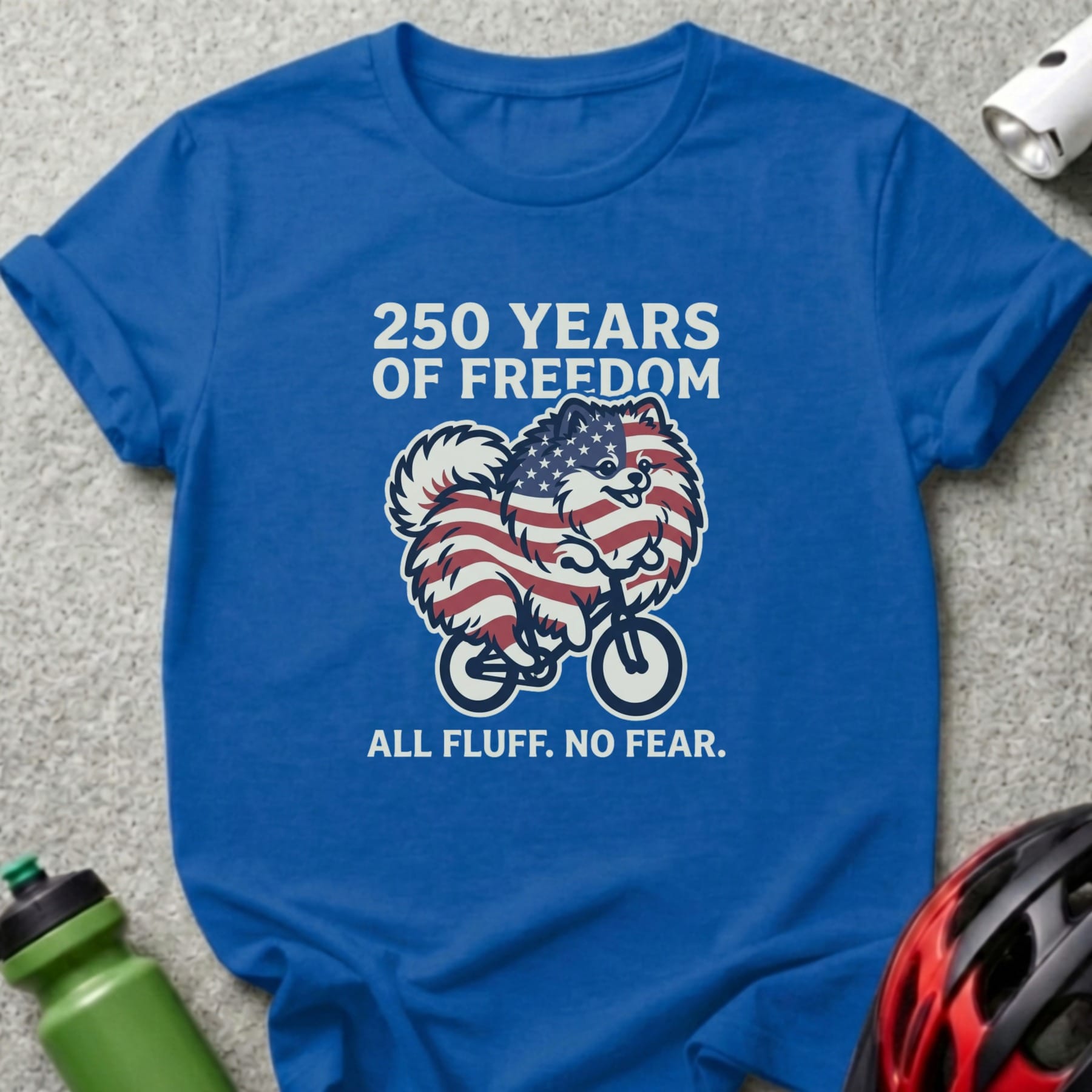 Pomeranian dog in American flag costume on bicycle, "250 Years of Freedom" text.