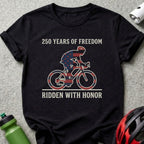 Black t-shirt with cyclist wearing USA flag pattern, "250 Years of Freedom, Ridden With Honor" text.