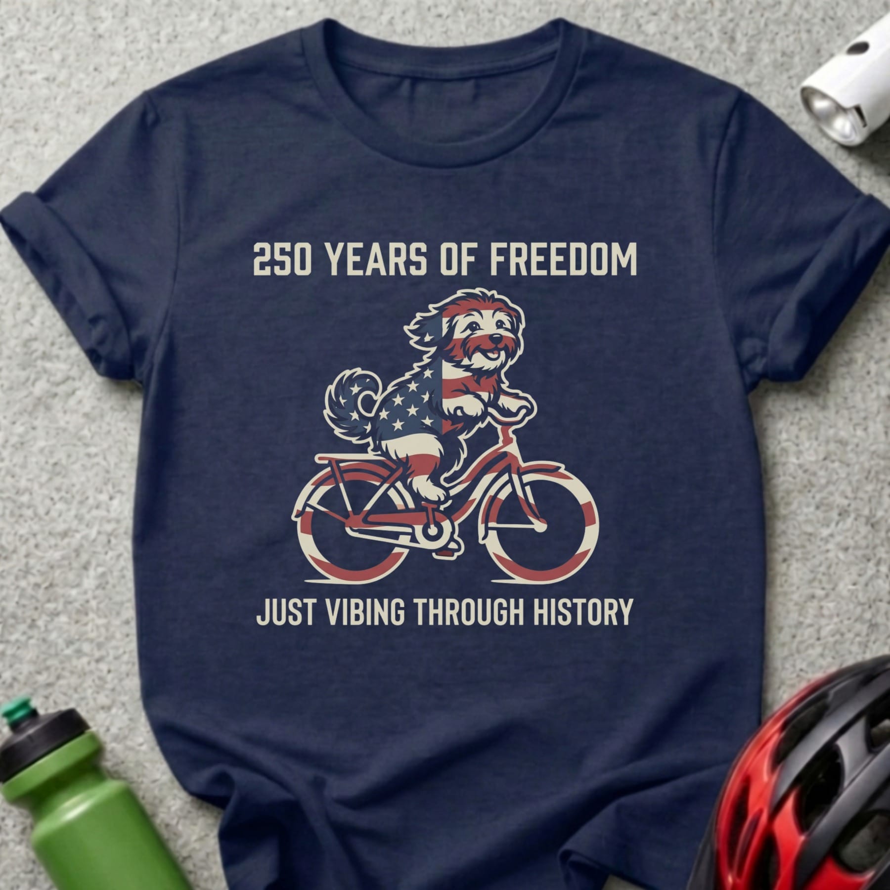 Navy t-shirt with dog riding bicycle, "250 Years of Freedom" and "Just Vibing Through History" text.
