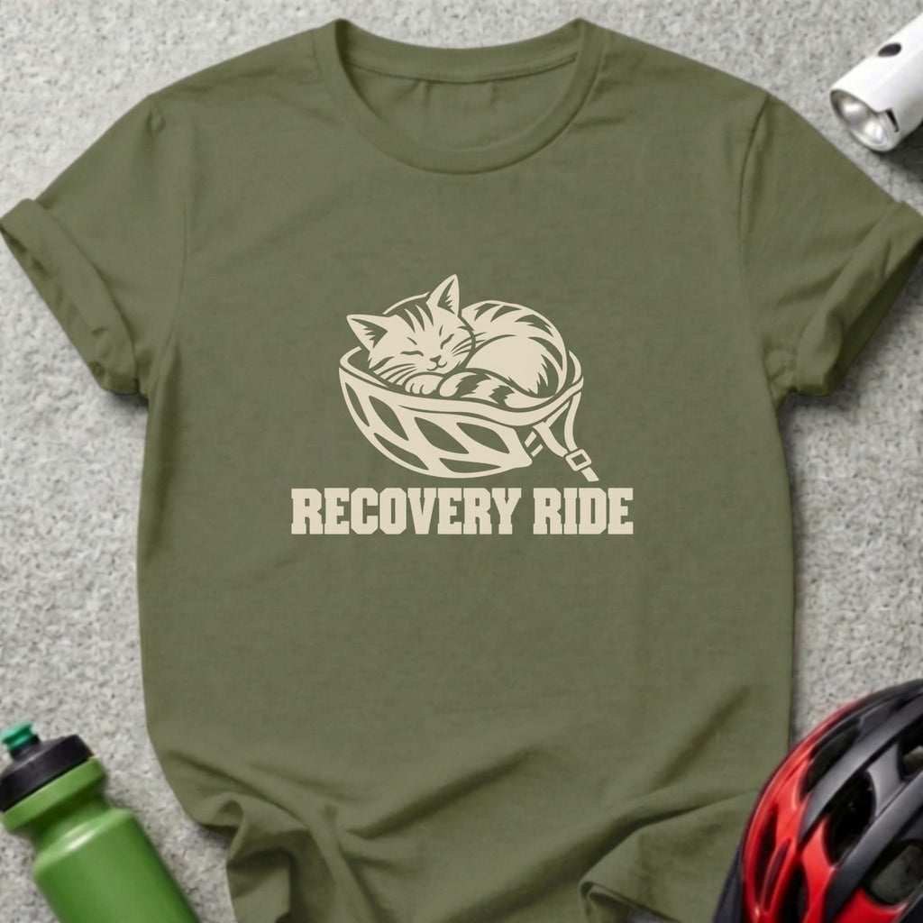 An olive green t-shirt featuring a cream graphic of a cat sleeping inside a bicycle helmet above the text "RECOVERY RIDE."