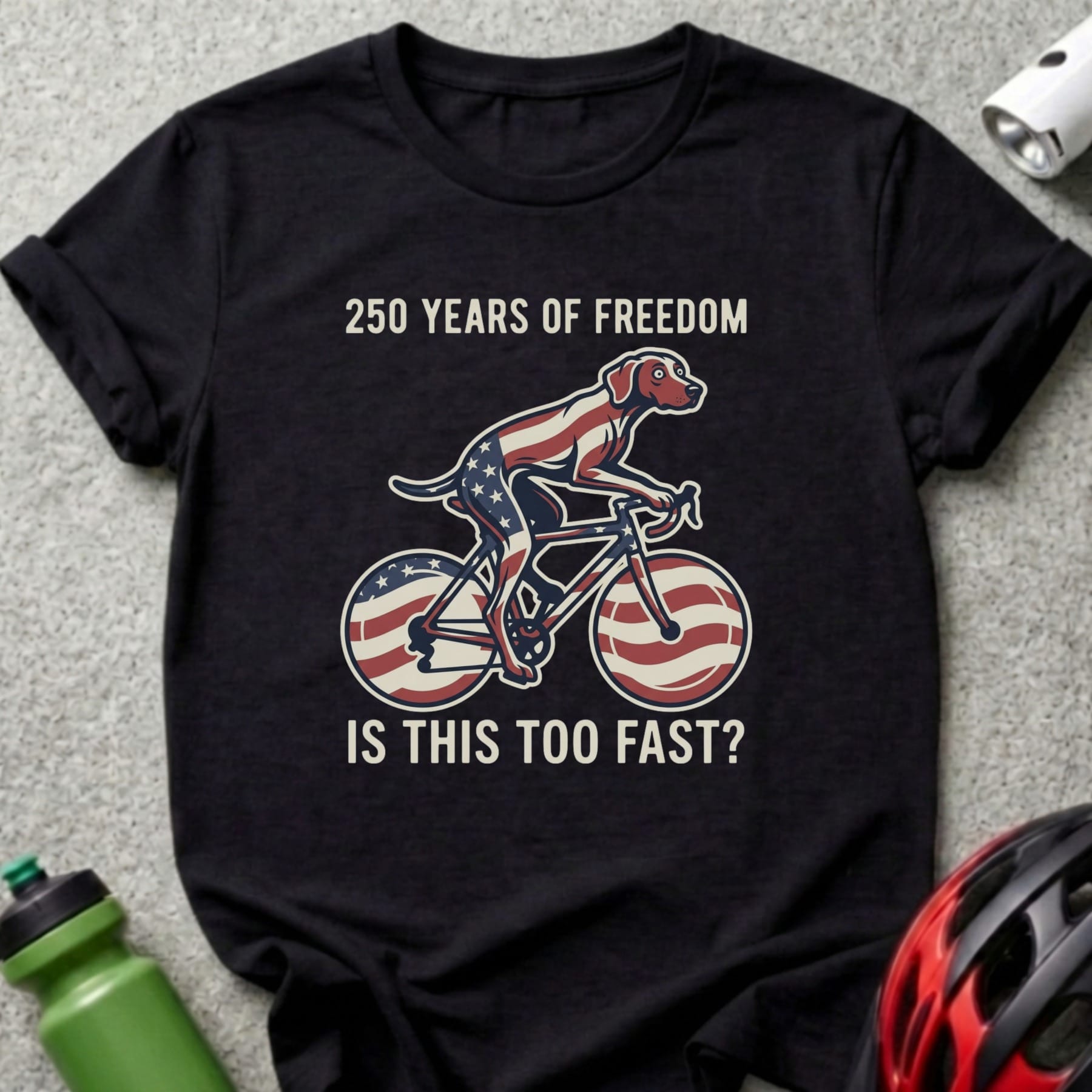 T-shirt with dog on bicycle, American flag pattern, and text "250 YEARS OF FREEDOM IS THIS TOO FAST?"