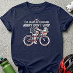 Navy t-shirt with "250 Years of Freedom Adopt Don't Shop" and bicyclist with dog.