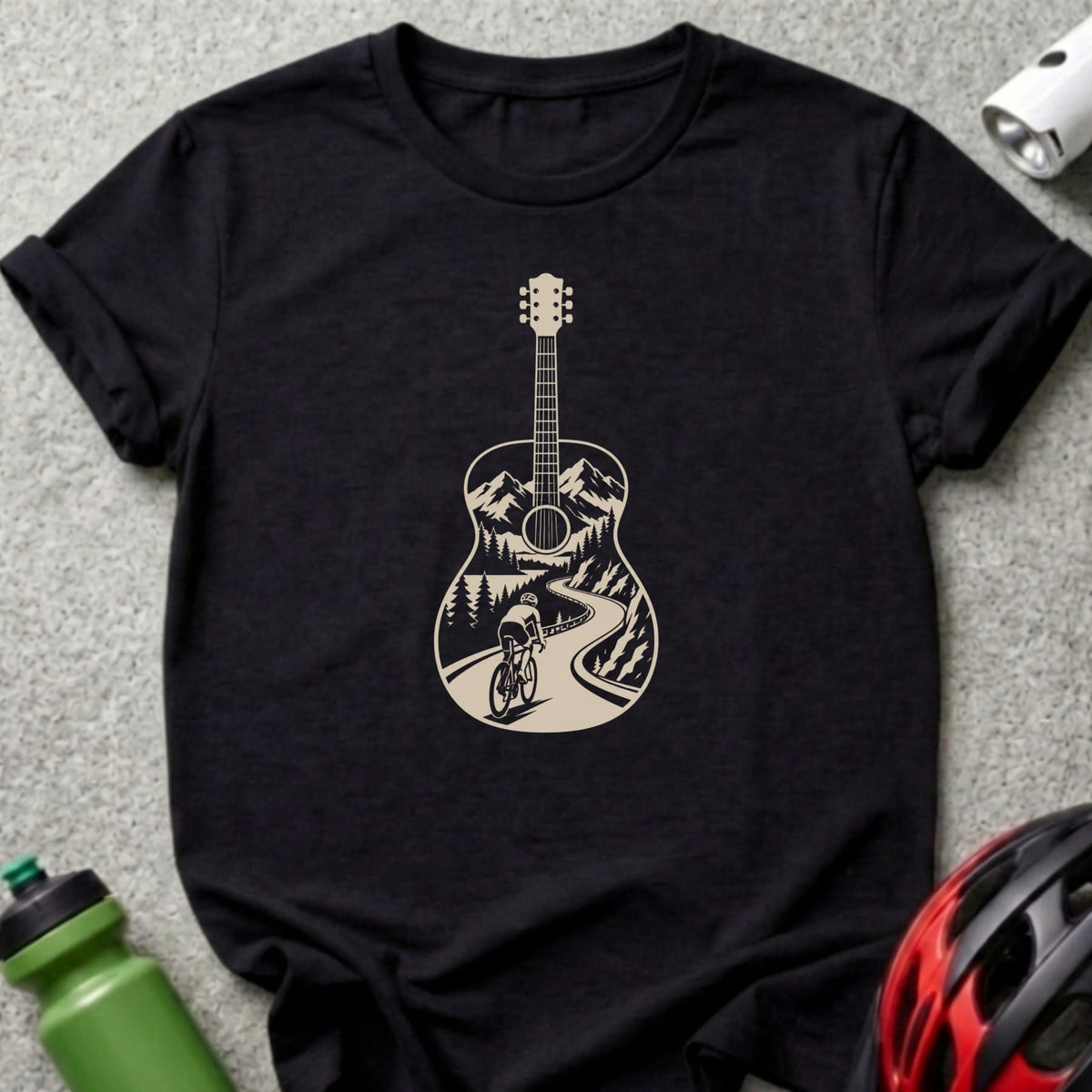 A black short-sleeved t-shirt features a white graphic of an acoustic guitar framing a mountain cycling scene.