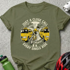 T-shirt with cyclist narrowly avoiding two yellow taxis, text "JUST A CLOSE CALL EVERY SINGLE RIDE".