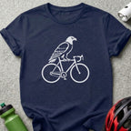 White eagle perched on a bicycle silhouette on a navy blue t-shirt.