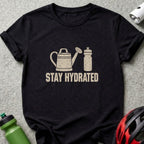 Black t-shirt featuring a graphic of a watering can and water bottle with the text Stay Hydrated.