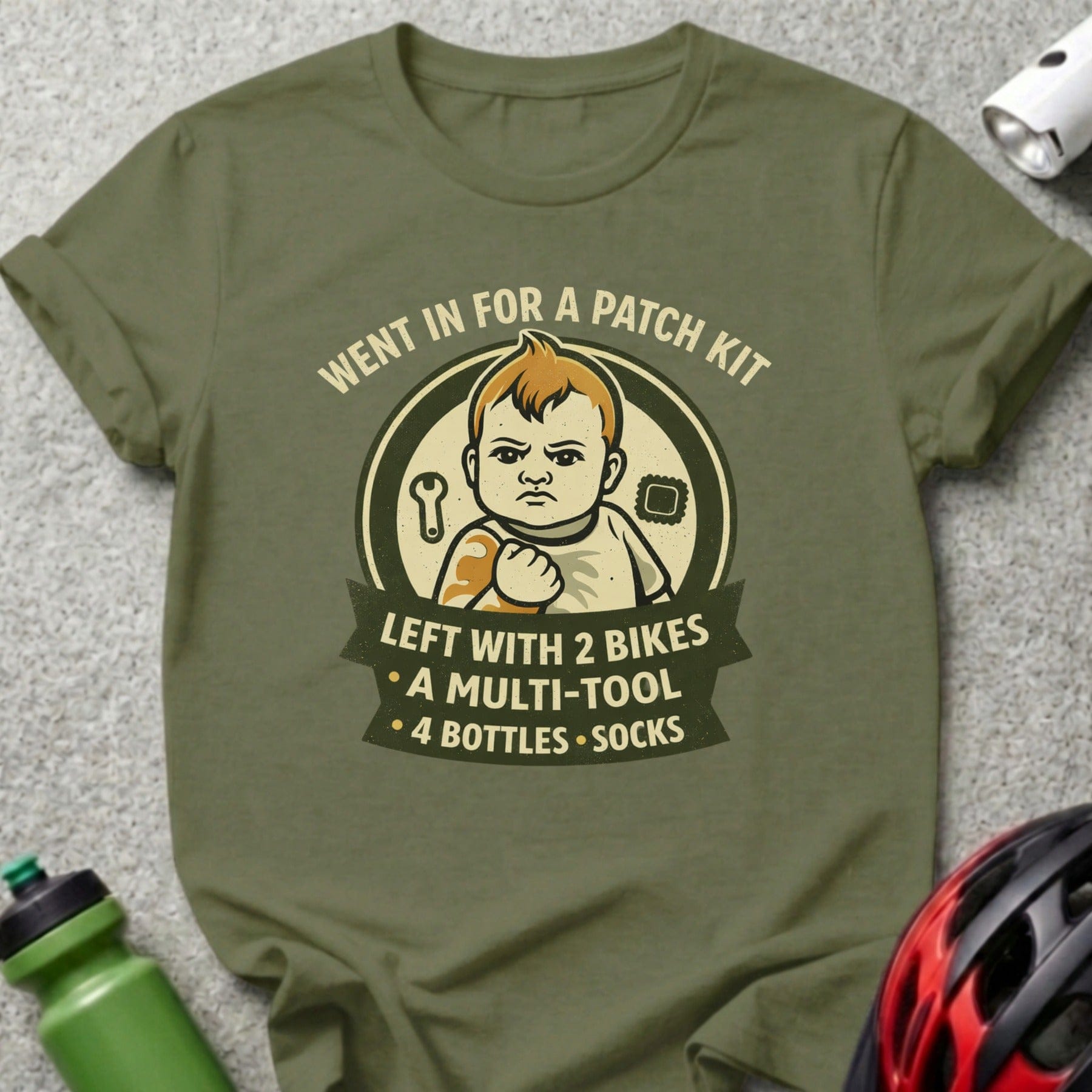 Olive green t-shirt with "Went in for a patch kit, left with 2 bikes..." text and baby graphic.