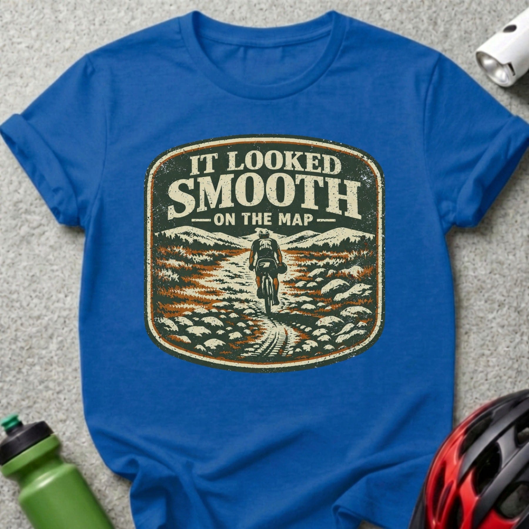 Blue t-shirt with "IT LOOKED SMOOTH ON THE MAP" graphic of cyclist on a trail.