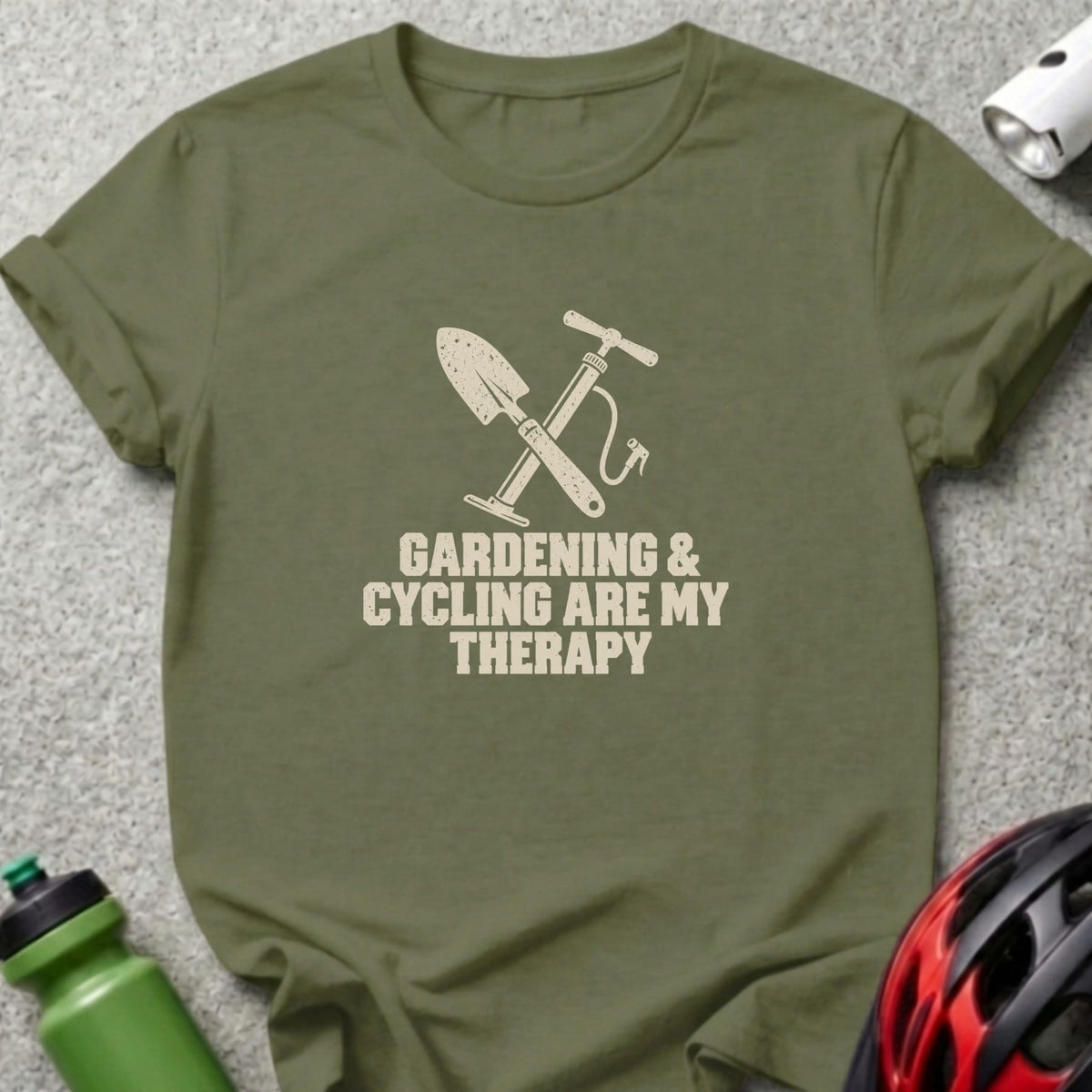 An olive green crewneck t-shirt featuring crossed shovel and bicycle pump graphics with the text Gardening and Cycling Are My Therapy.