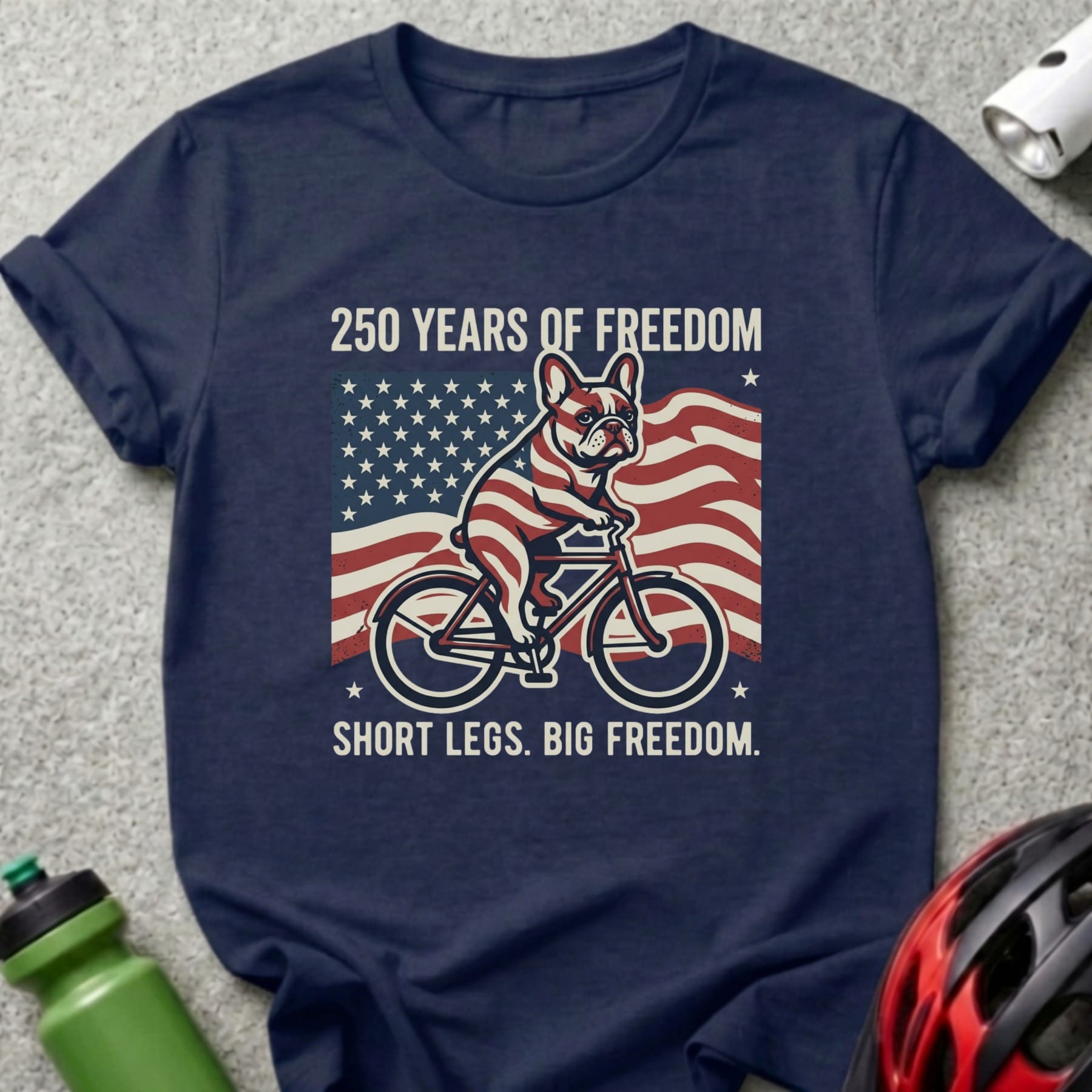 French bulldog on bicycle with American flag, "250 Years of Freedom. Short legs. Big Freedom."