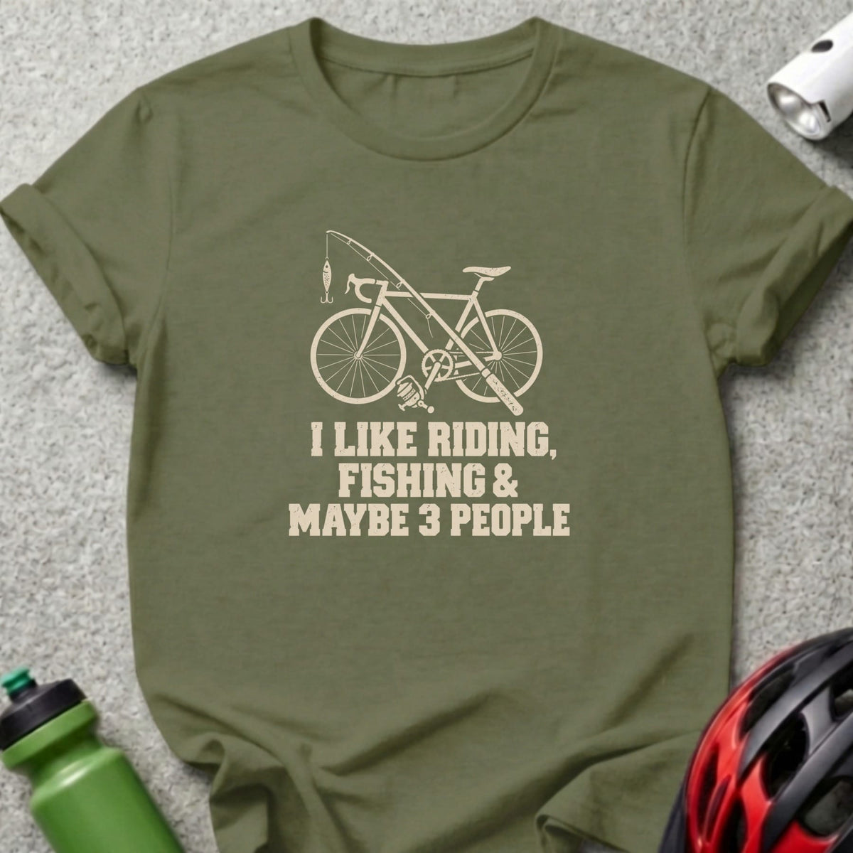 Olive green t-shirt with a white graphic of a bicycle, fishing rod, and text reading I LIKE RIDING, FISHING & MAYBE 3 PEOPLE.