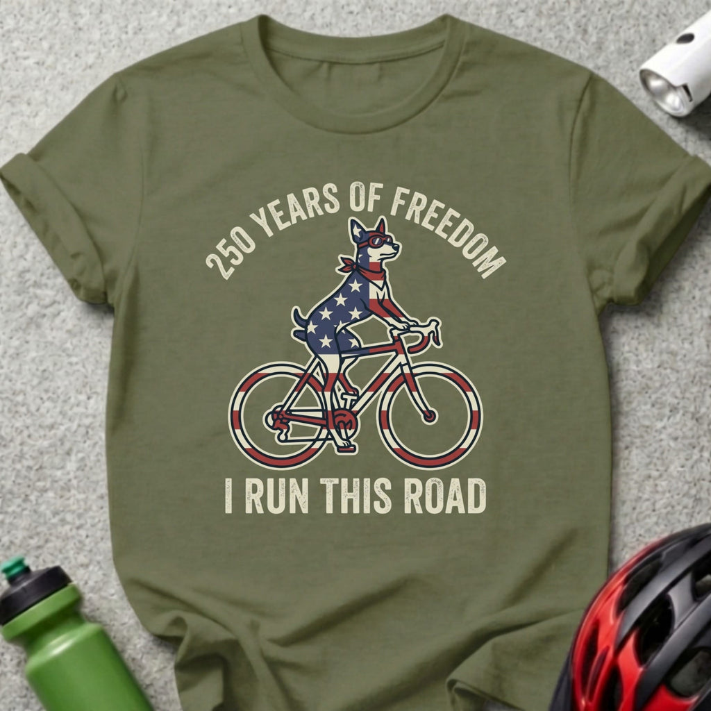 Dog in American flag bandana rides a bicycle, text "250 Years of Freedom I Run This Road".