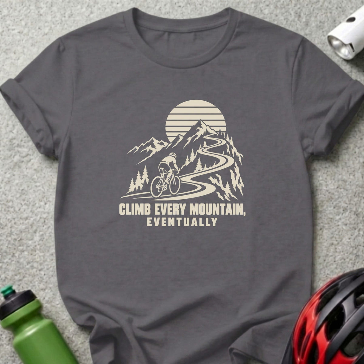 Charcoal t-shirt featuring a graphic of a cyclist climbing a mountain road with the text CLIMB EVERY MOUNTAIN, EVENTUALLY.