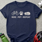 Navy t-shirt with bicycle, paw print, and cat icons above "RIDE • PET • REPEAT".