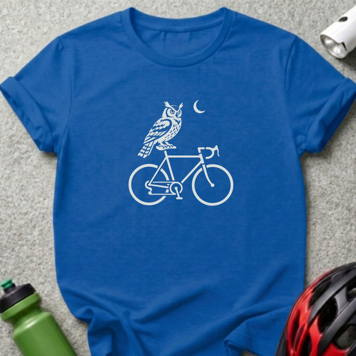 Blue t-shirt featuring a white graphic of an owl on a bicycle under a crescent moon.